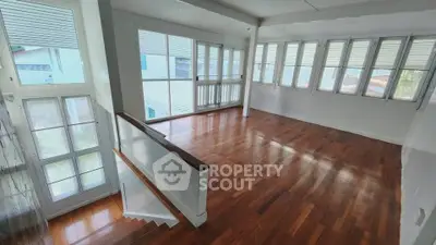 Spacious sunlit room with hardwood floors and large windows, perfect for a bright living area.