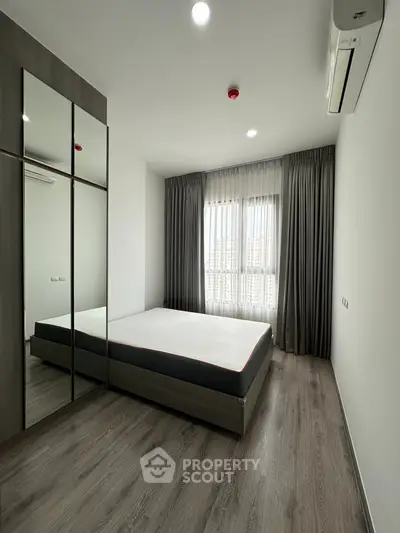 Modern bedroom with sleek design, large window, and mirrored wardrobe in a stylish apartment.