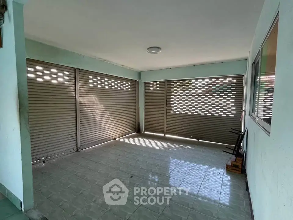 Spacious tiled garage with ample natural light and secure shutter doors.