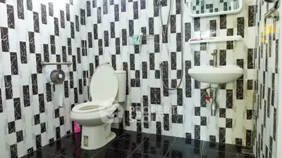 Modern bathroom with unique black and white tile design and compact fixtures.