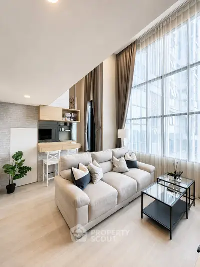 Modern living room with high ceilings, large windows, and stylish decor in a luxury apartment.