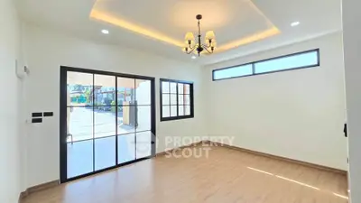 Spacious living room with elegant chandelier and large windows offering natural light.