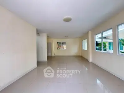 Spacious empty living room with large windows and tiled flooring, perfect for customization.