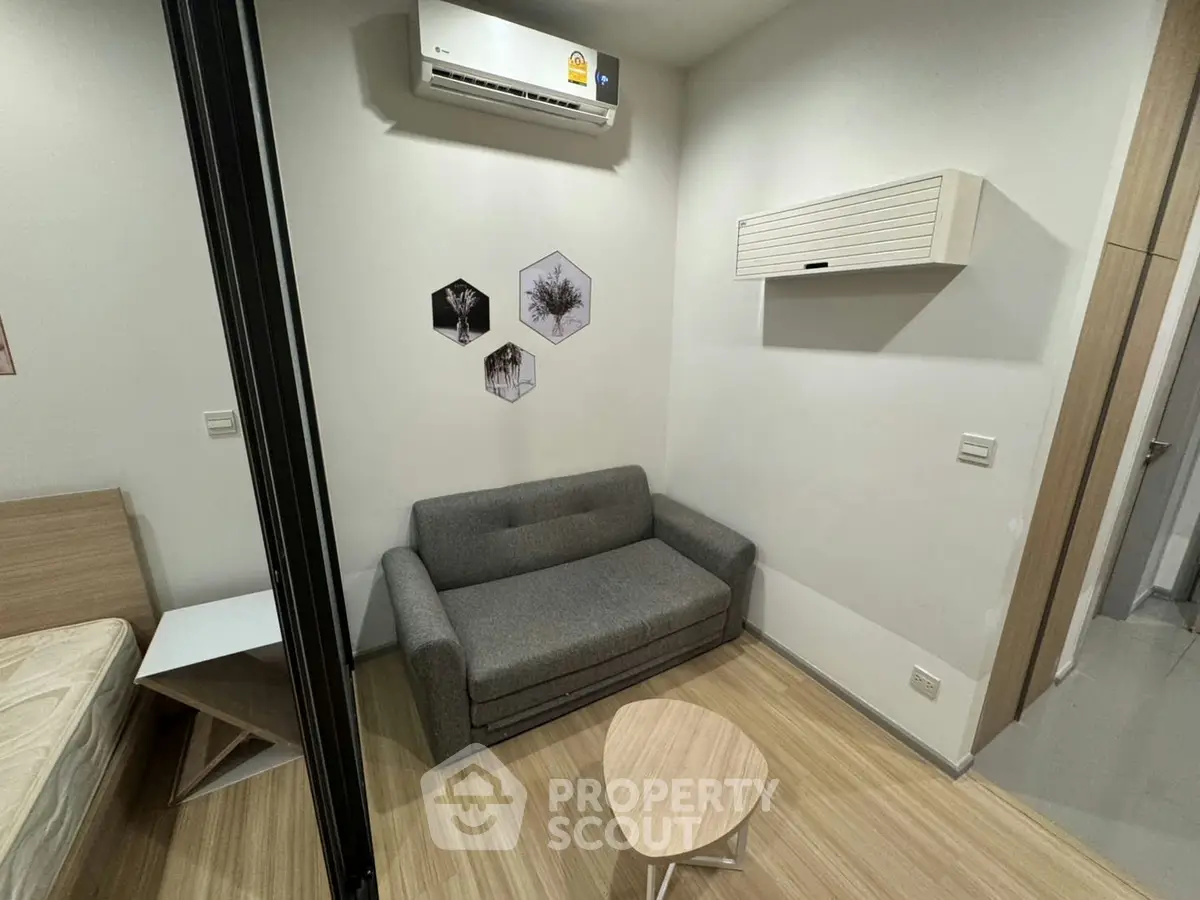 Cozy modern living room with compact sofa and stylish decor in a minimalist apartment.