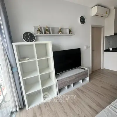 Modern living room with sleek TV stand, wall clock, and air conditioning in a stylish apartment.