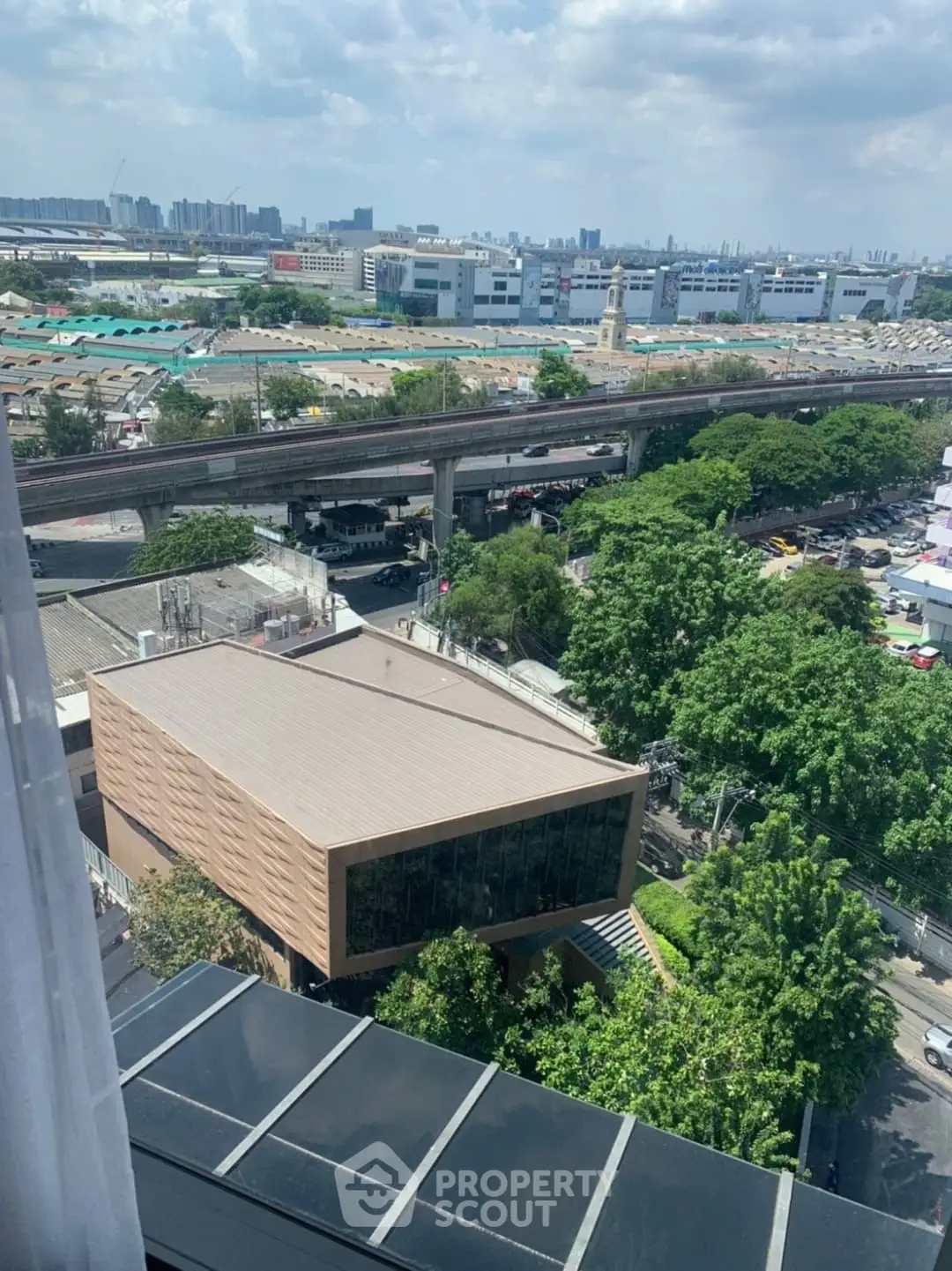 Stunning cityscape view from high-rise building with lush greenery and urban skyline.