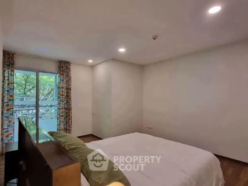 Cozy bedroom with large window and modern decor in a serene residential setting.