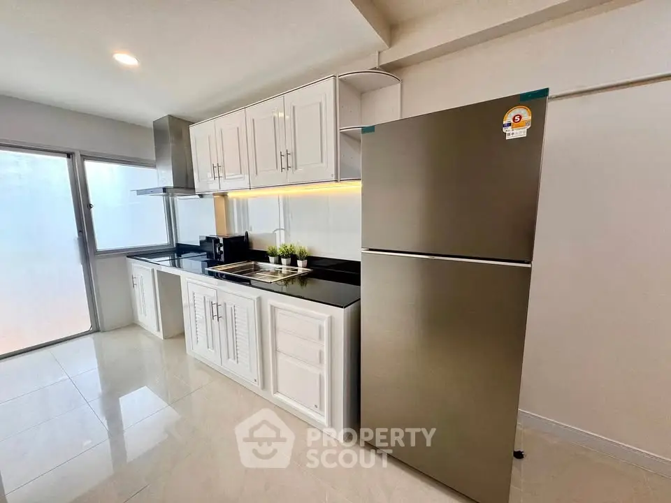Modern kitchen with sleek stainless steel fridge and elegant cabinetry in a bright, spacious layout.