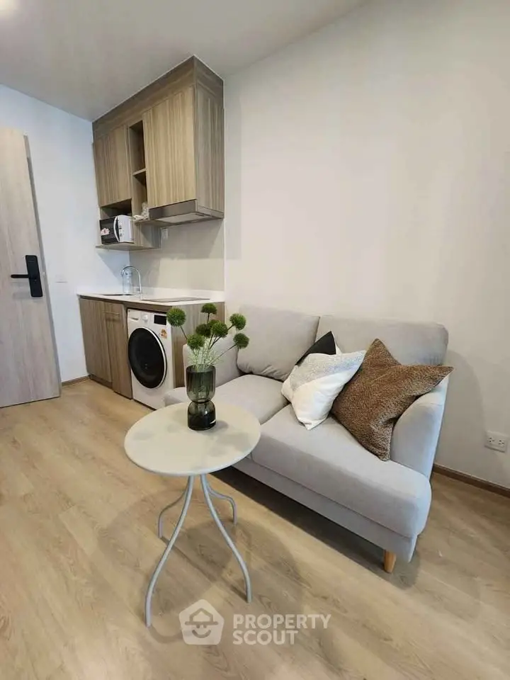 Cozy living room with compact kitchen, featuring a washing machine and modern decor.