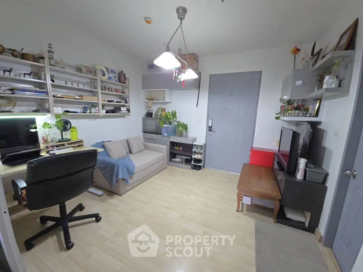 Cozy living room with modern decor and workspace, featuring shelves and a comfortable sofa.