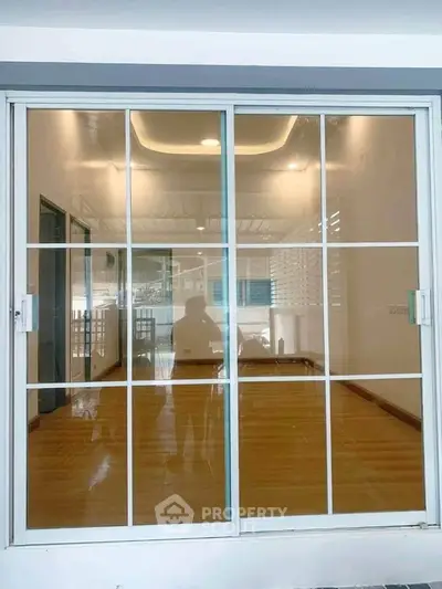 Spacious room with large glass sliding doors and wooden flooring, ideal for natural light and modern living.
