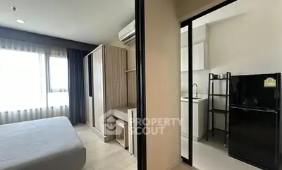 Modern apartment interior with bedroom and compact kitchen featuring sleek design and natural light.