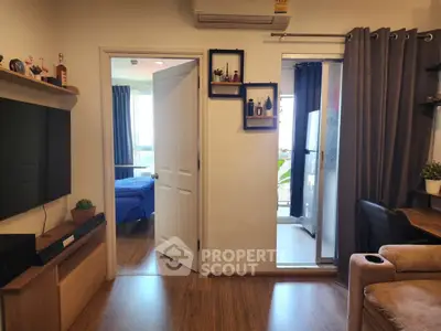 Modern living room with open view to bedroom and balcony, featuring stylish decor and wooden flooring.