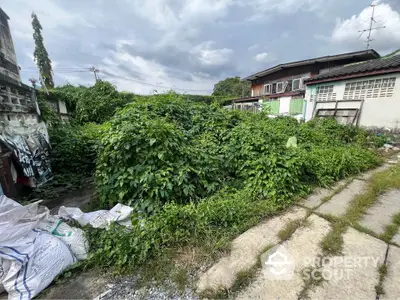 Vacant land with overgrown vegetation in a residential area, ideal for development opportunities.