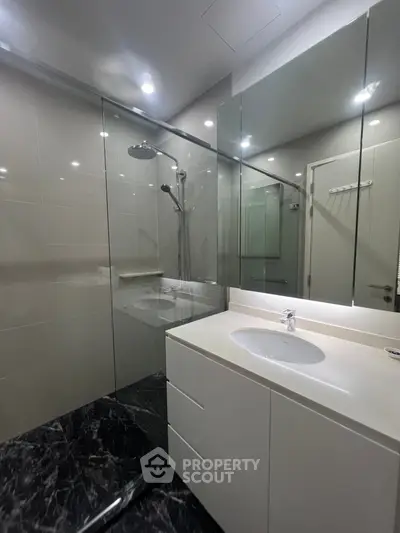 Modern bathroom with glass shower and sleek vanity in luxury apartment.