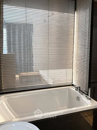 Modern bathroom with sleek bathtub and blinds, offering a serene and stylish retreat.