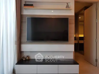 Modern living room with wall-mounted TV and sleek cabinetry in stylish apartment.