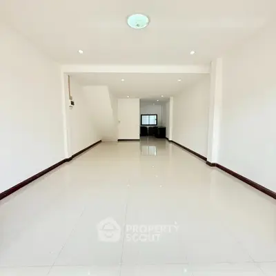 Spacious open-plan interior with sleek white tiles and recessed lighting.