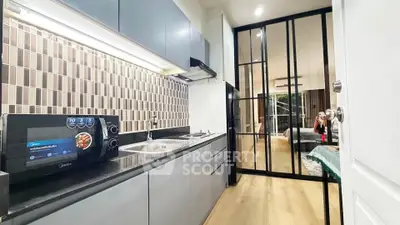 Modern kitchen with sleek cabinetry and open layout leading to a cozy living area.
