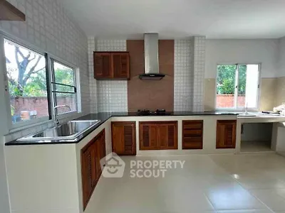 Spacious kitchen with modern design, featuring wooden cabinets and large windows for natural light.