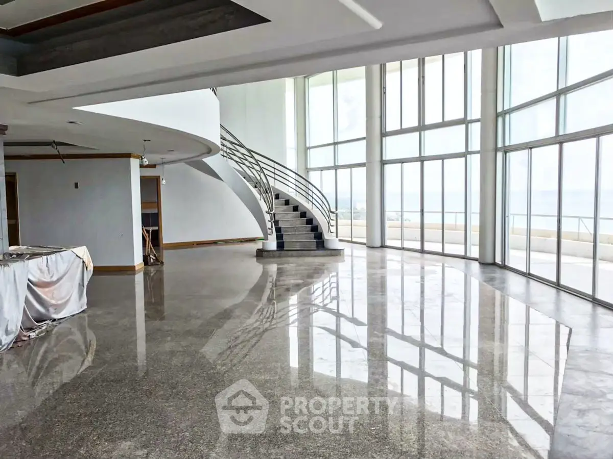 Luxurious open-plan living room with stunning ocean views and elegant spiral staircase.
