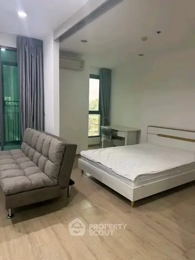 Modern studio apartment with bed, sofa, and balcony view