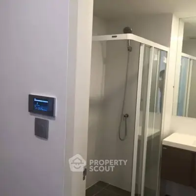 Modern bathroom with glass shower enclosure and sleek vanity unit.