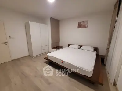 Spacious minimalist bedroom with modern wooden bed and ample storage.