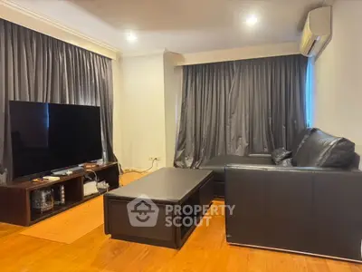 Spacious living room with modern black leather sofa and large TV setup.
