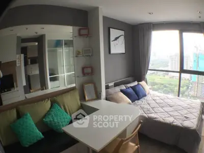 Modern studio apartment with cozy bed and city view, featuring stylish decor and ample natural light.