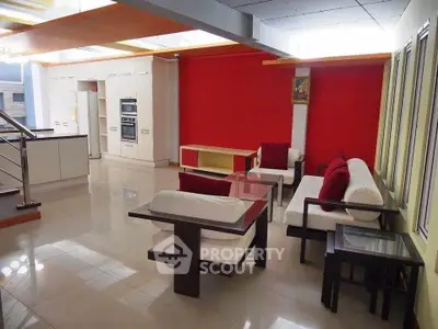Spacious modern living room with open kitchen and stylish red accent wall