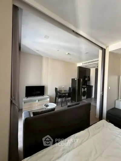 Modern open-plan living room with sleek kitchen and dining area, featuring contemporary furniture and natural light.
