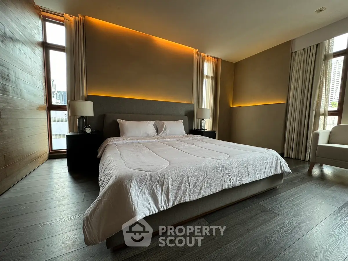 Luxurious bedroom with modern lighting and large windows in a high-rise apartment.