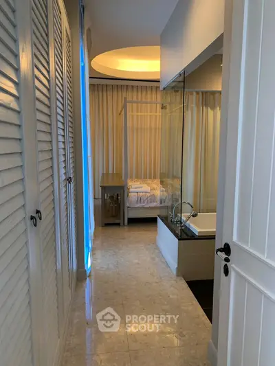 Stylish bedroom with glass-enclosed bathtub and elegant lighting