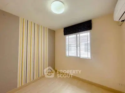 Bright empty room with striped accent wall and window, ideal for customization.