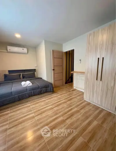 Spacious bedroom with modern design and wooden flooring, featuring a cozy bed and ample wardrobe space.