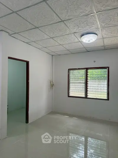 Spacious room with tiled floor and decorative ceiling, featuring a large window for natural light.