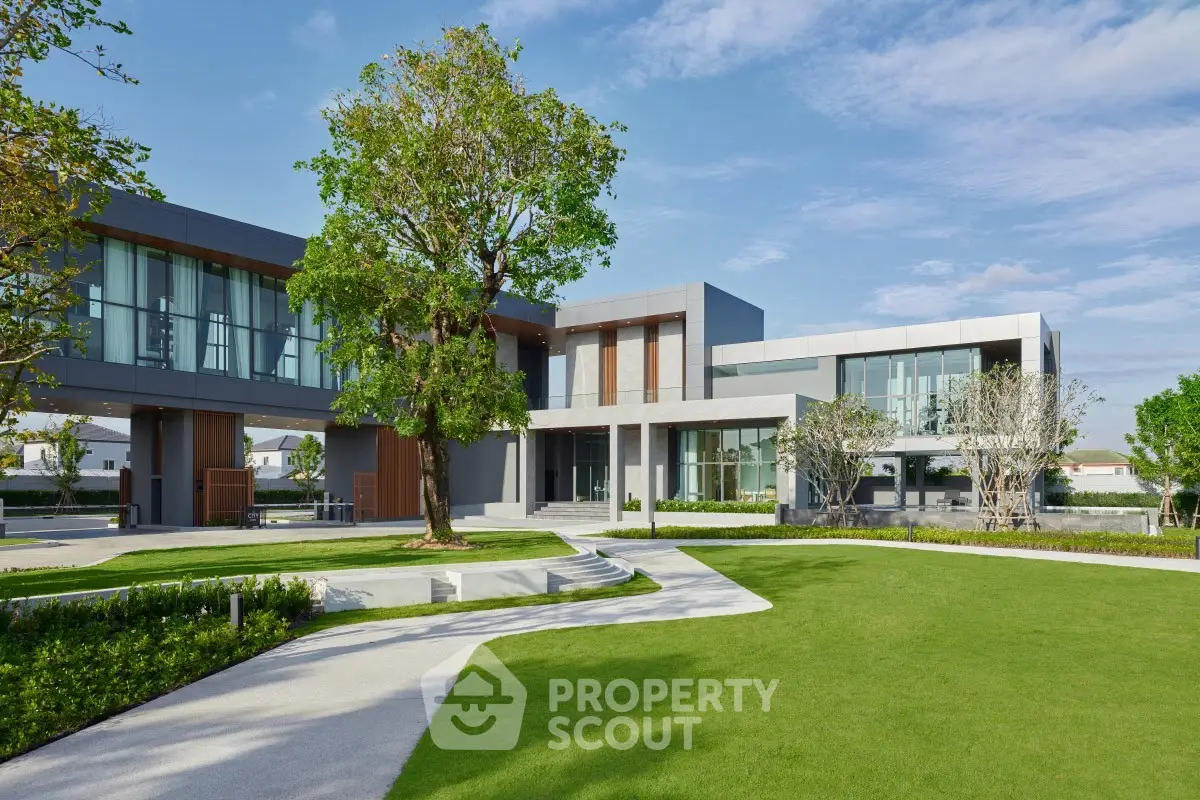 Modern luxury home with expansive lawn and contemporary architecture under a clear blue sky.