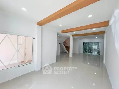 Spacious modern living room with glossy tiled floors and unique ceiling beams
