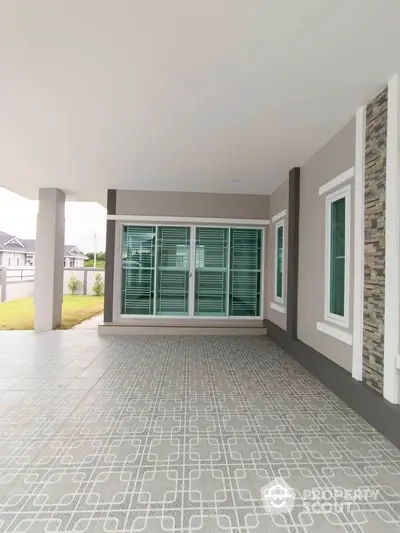 Spacious modern home exterior with large windows and stylish tiled patio.