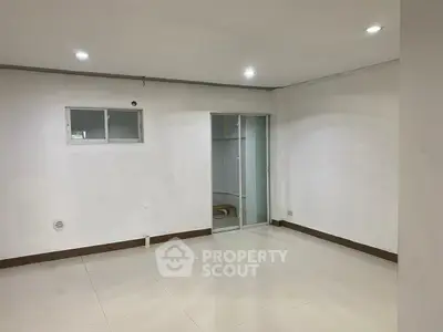 Spacious empty room with tiled floor and sliding glass door, ideal for customization.