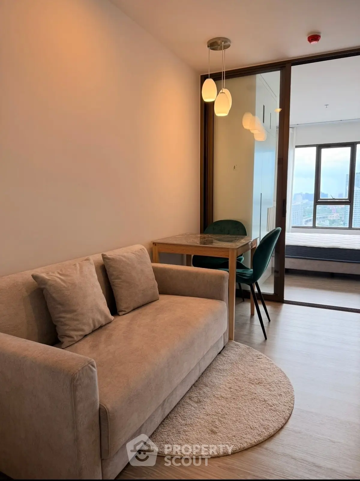Modern living room with cozy sofa and dining area, featuring a view into a stylish bedroom.