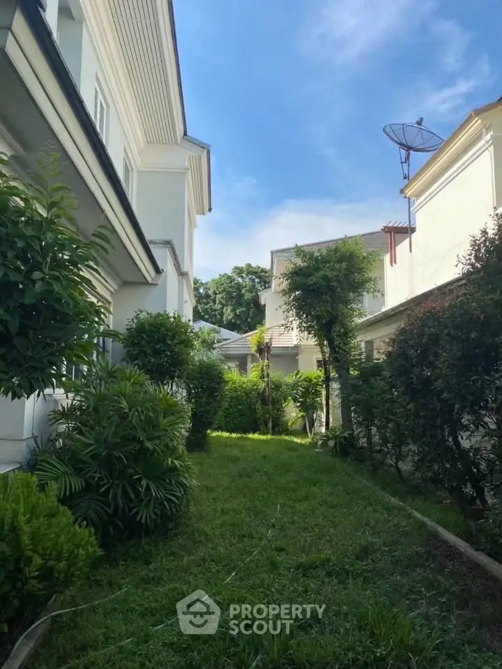Charming garden view between elegant residential buildings under a clear blue sky.