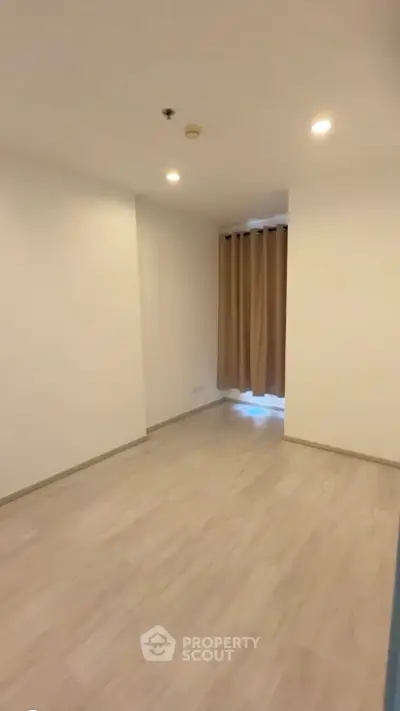 Spacious empty room with wooden flooring and large window, perfect for customization.