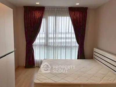 Spacious bedroom with large window and elegant curtains in modern apartment.