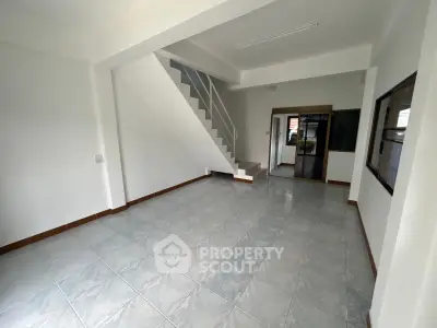 Spacious empty living room with tiled flooring and staircase, ideal for customization.