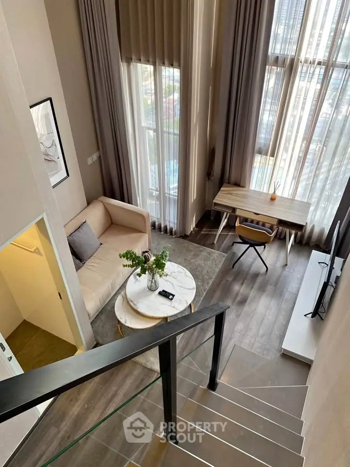 Modern loft apartment with high ceilings, stylish living area, and large windows offering natural light.