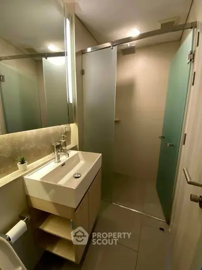 Modern bathroom with sleek shower and stylish vanity in contemporary apartment.