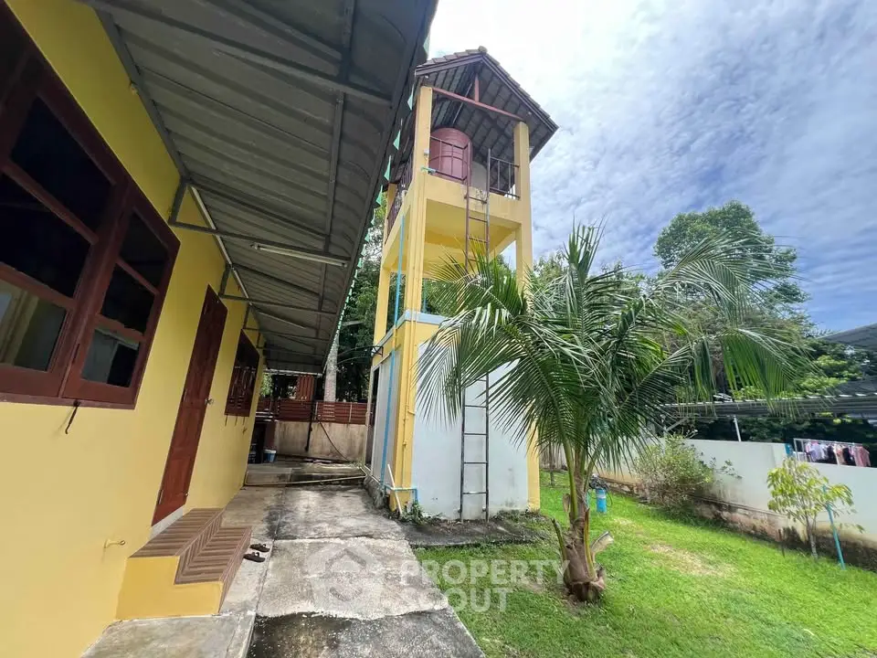 Charming yellow house with unique water tower and lush greenery