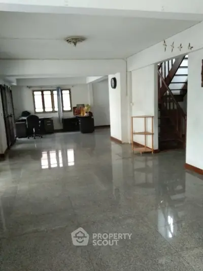 Spacious open-plan interior with polished floors and staircase, ideal for versatile living or office space.